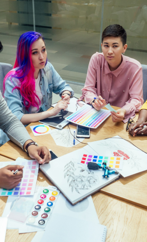 creative agency designer team working together:african american woman with dreadlocks pigtails and caucasian girl pink blue multi-colored hair communication with indian man in office.
